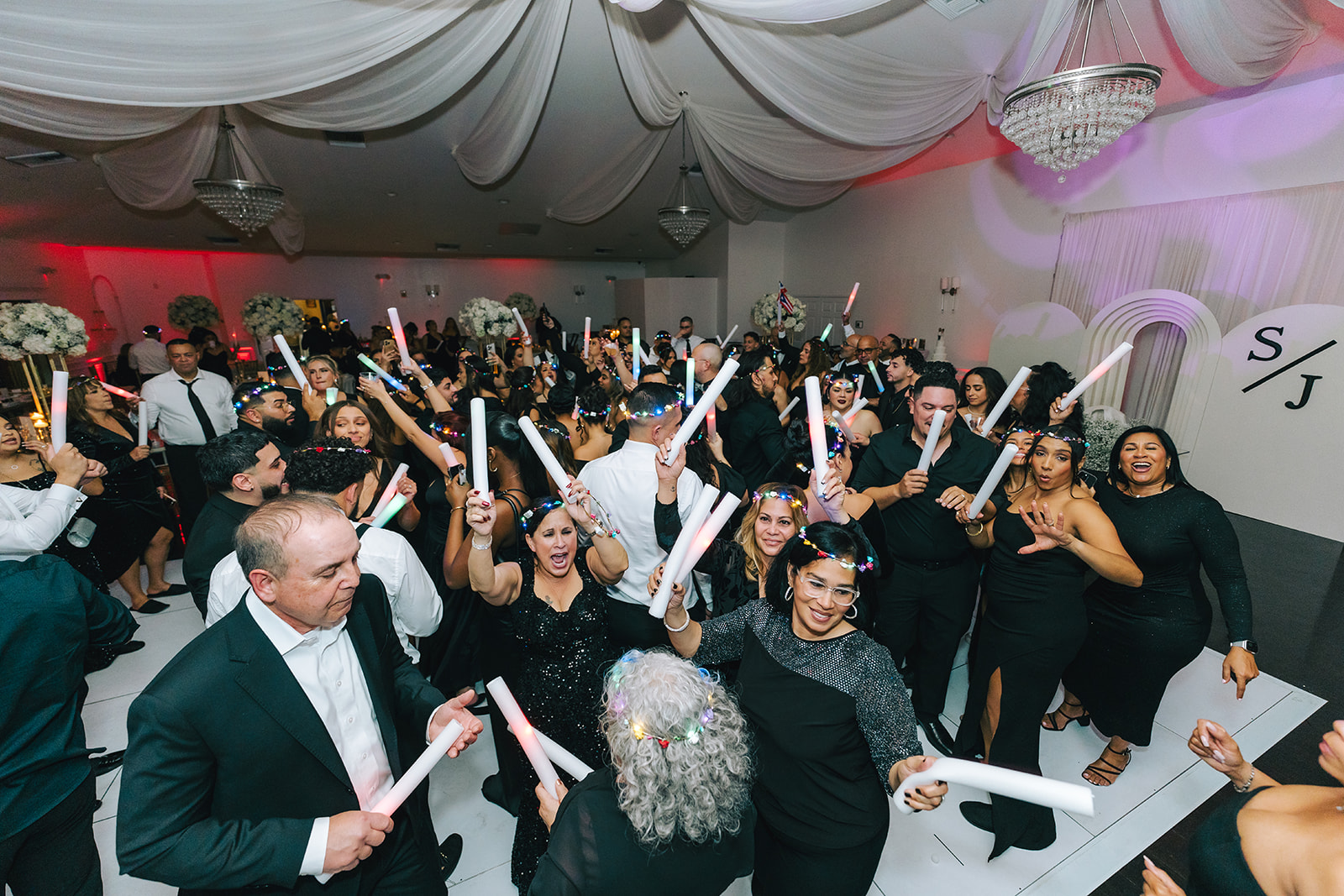 Guests celebrating with LED foam sticks on a packed wedding dance floor