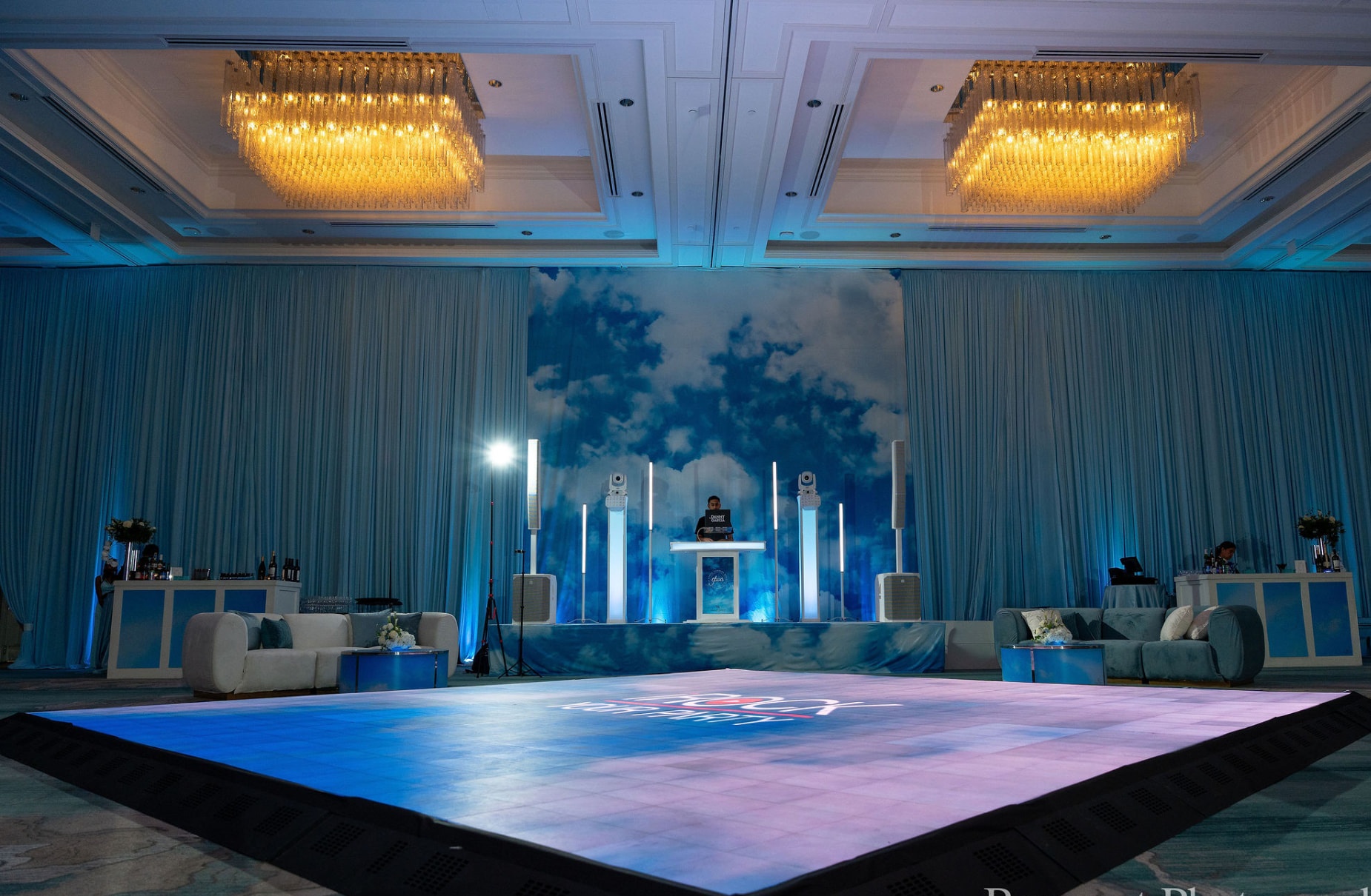 Elegant corporate event ballroom with chandeliers, custom dance floor, and DJ setup